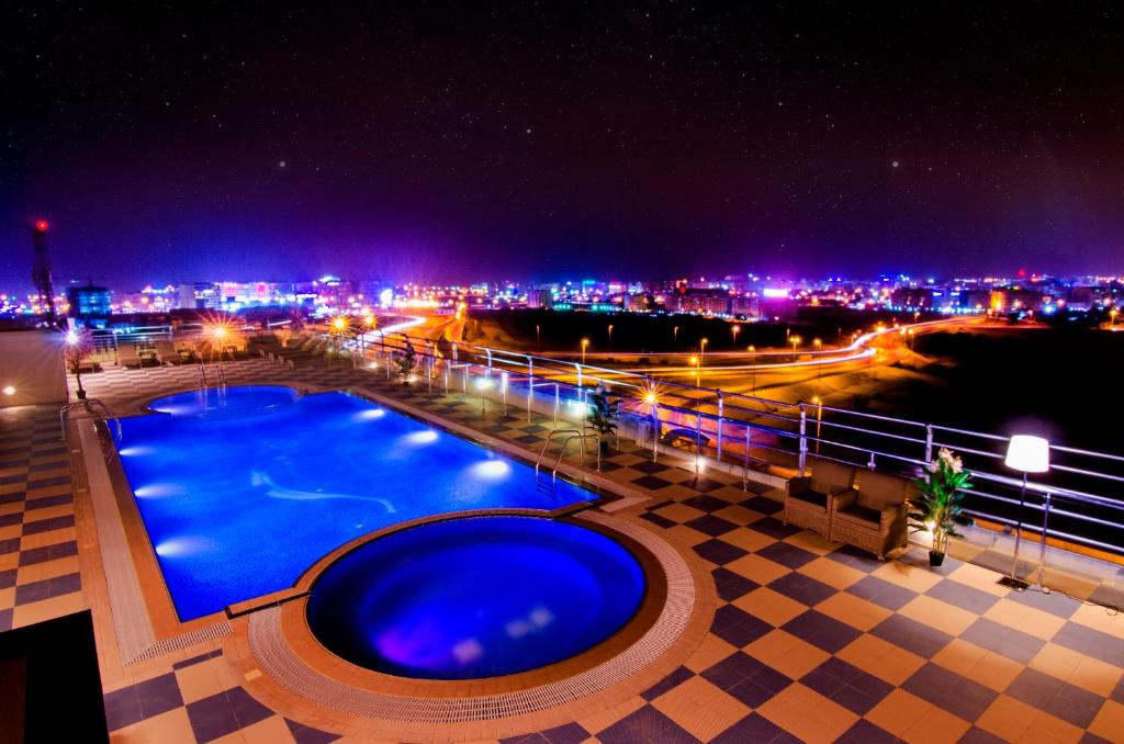 马斯喀特Al Murooj Grand Hotel的享有城市美景的夜间游泳池
