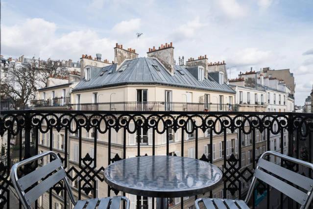 巴黎美妙停留酒店的阳台配有桌椅,与大楼相连