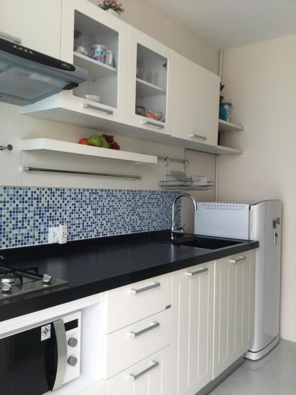 普吉镇Best Point Condominium Cape Panwa的厨房配有白色橱柜和黑色台面