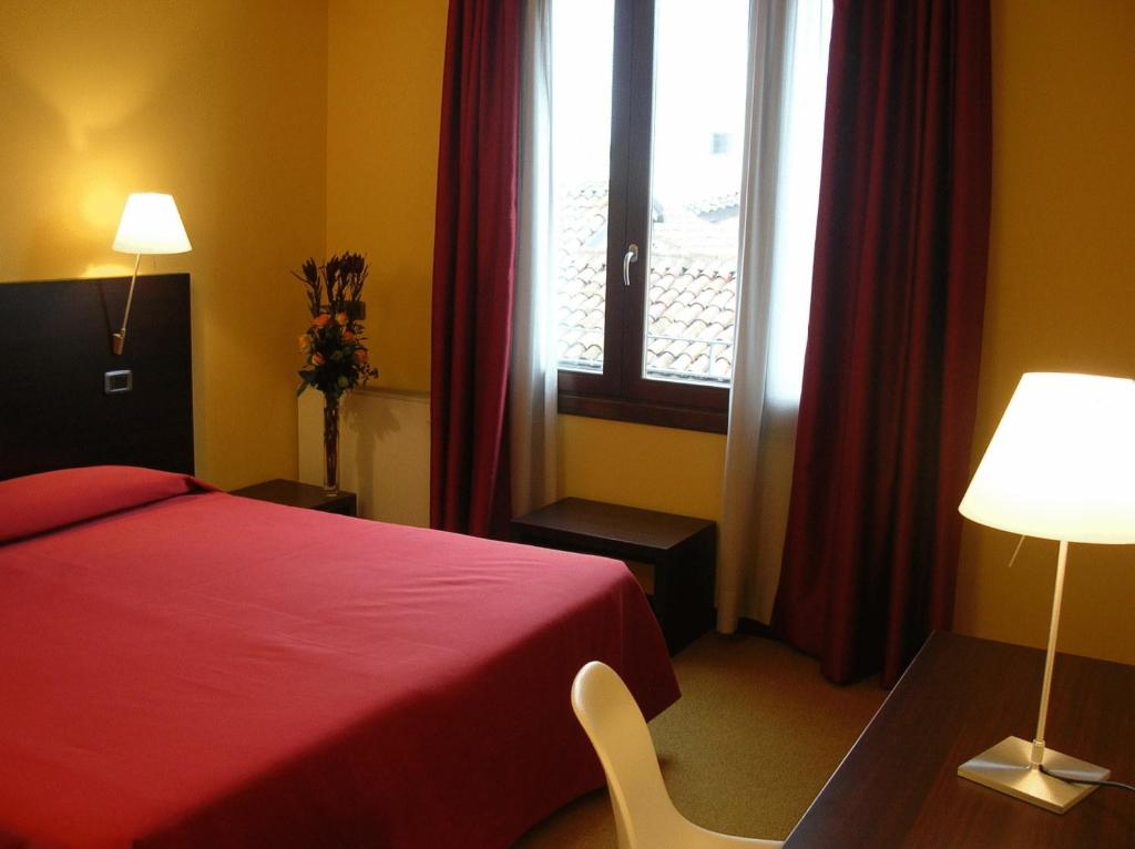 帕多瓦艾尔伯格威尔第酒店的酒店客房设有红色的床和窗户。