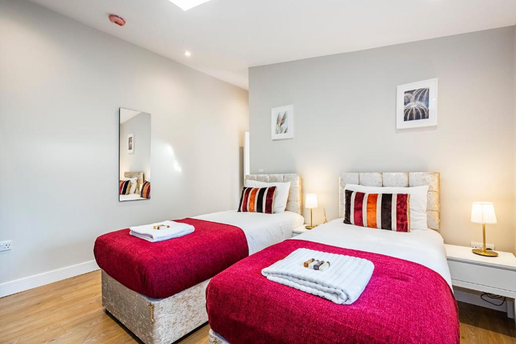 伦敦South Woodford 2 Bed En-Suite House的卧室内的两张床,配有红色毯子