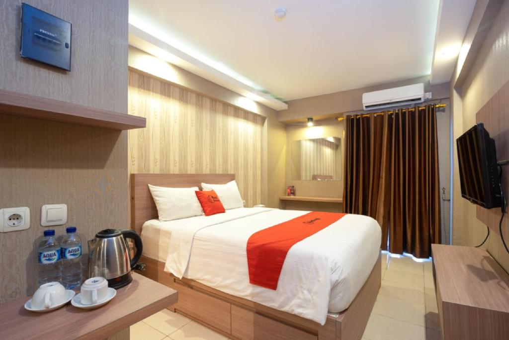 茂物RedDoorz Apartment at Bogor Valley的酒店客房,配有床和电视