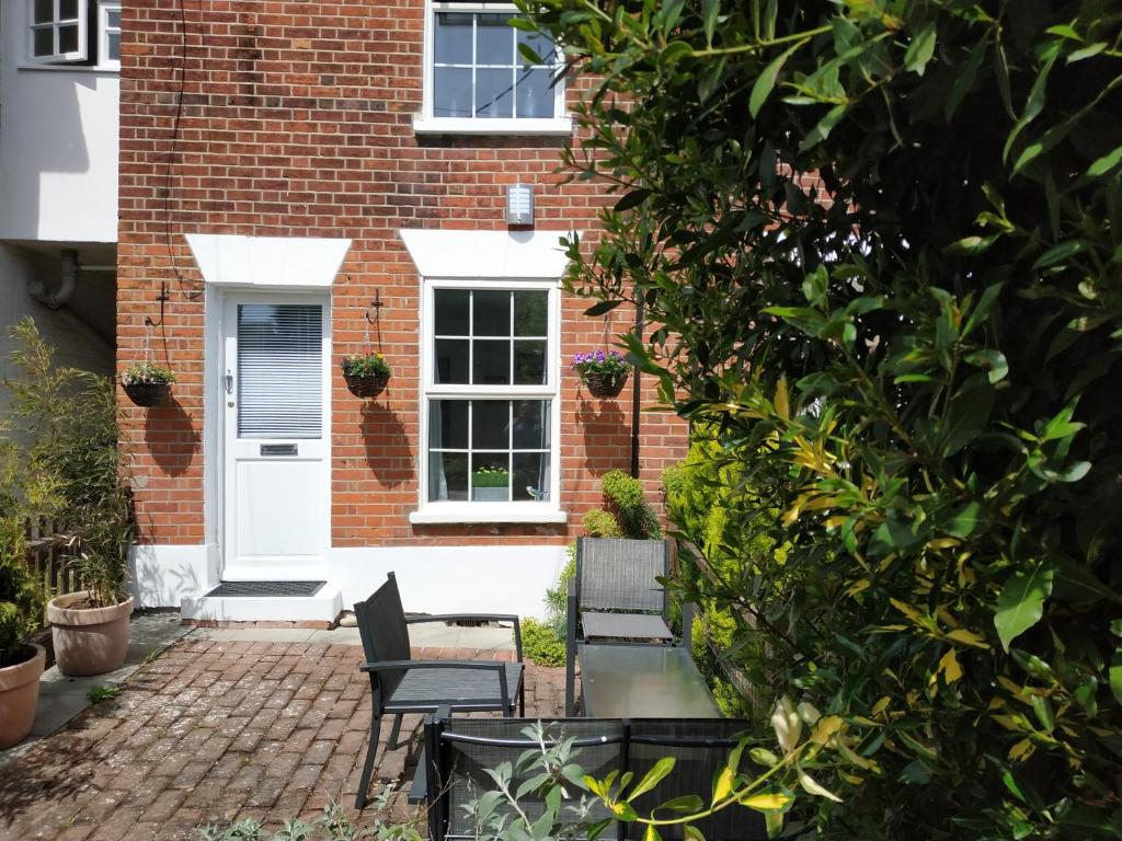 WivenhoeSecret Cottage, Wivenhoe - Charming, Cosy, Convenient & Quiet, 2 x Double Bed Period Cottage PLUS Patio - 6 min walk train, 2 min walk High Street Pubs, Restaurants, Shops的砖屋,配有两把椅子和一张桌子