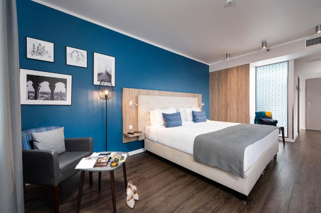 布达佩斯Three Corners Lifestyle Hotel的一间卧室配有一张大床和一把椅子