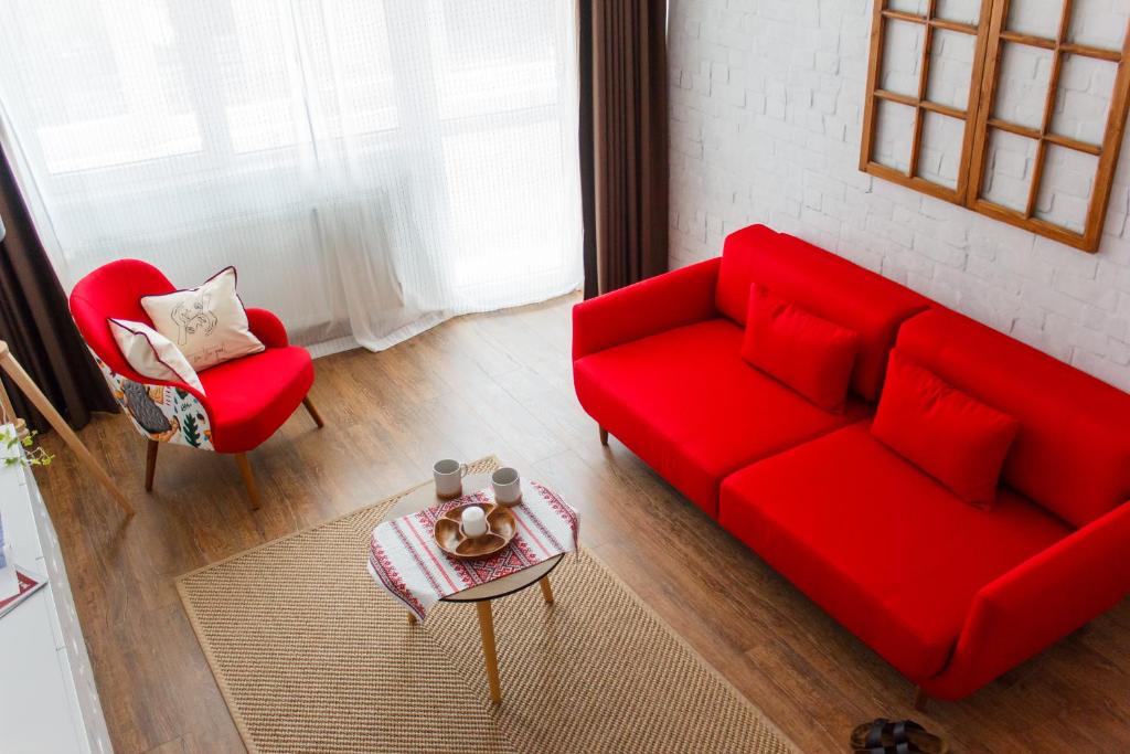 布加勒斯特豪华住宿公寓　的客厅配有红色的沙发和两把椅子