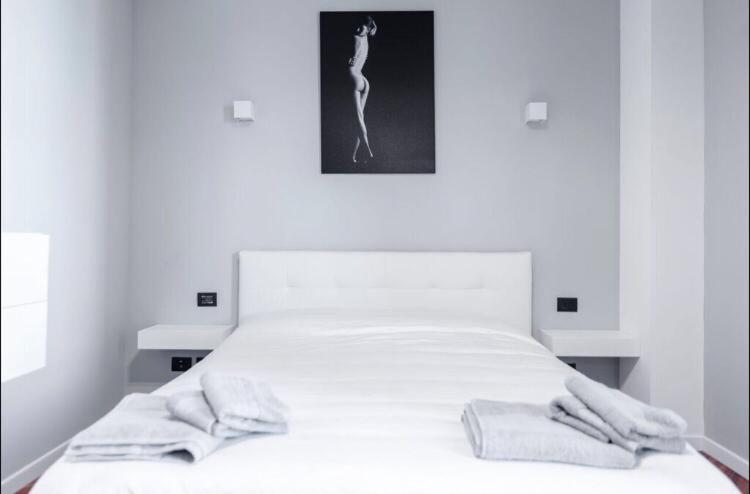 卡萨诺达达Le residenze dell'Adda的卧室配有白色的床和2条毛巾