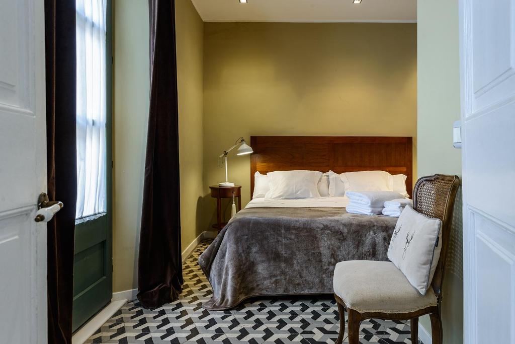 赫罗纳APG Espais Rambla的卧室配有床、椅子和窗户。