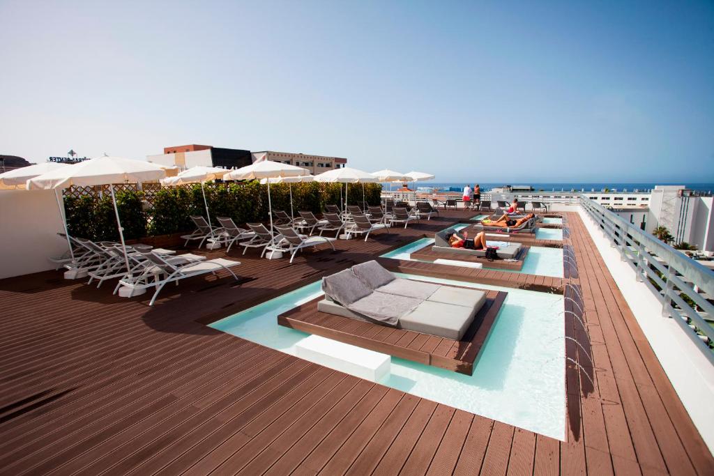 美洲海滩Coral Suites & Spa - Adults Only的一个带椅子和遮阳伞的屋顶甲板和大海