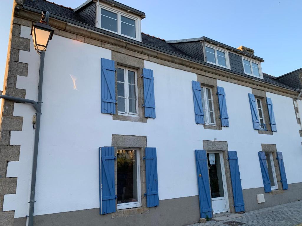 伊勒蒂迪Jolie maison au port de l’Ile Tudy的白色的建筑,有蓝色百叶窗和街灯