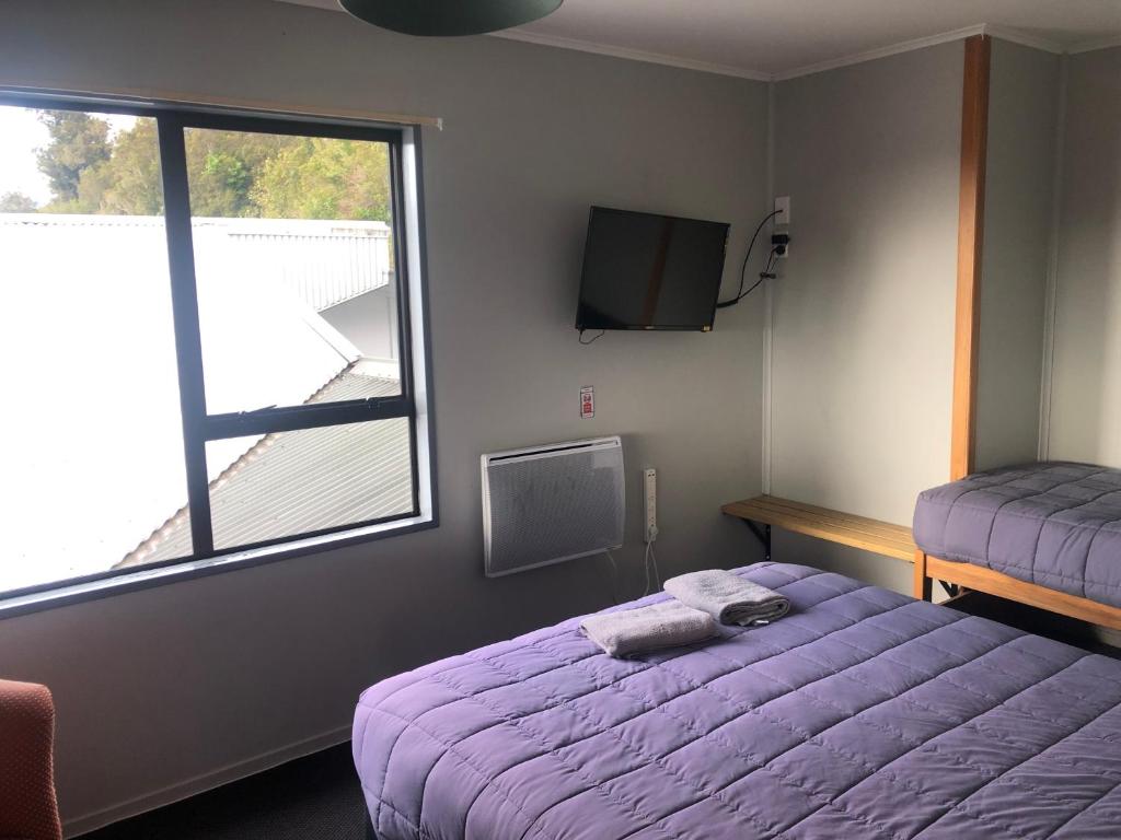 福克斯冰川Ivorytowers Accommodation的一间卧室设有紫色的床和窗户