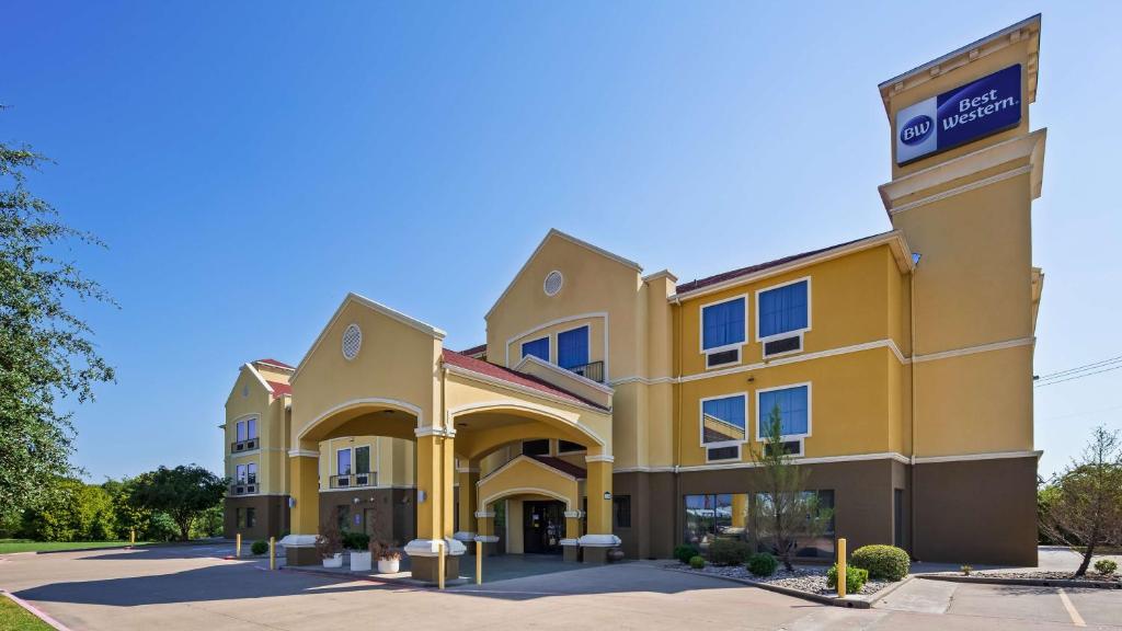 科西卡纳Best Western Executive Inn Corsicana的一座黄色的大建筑,上面有标志