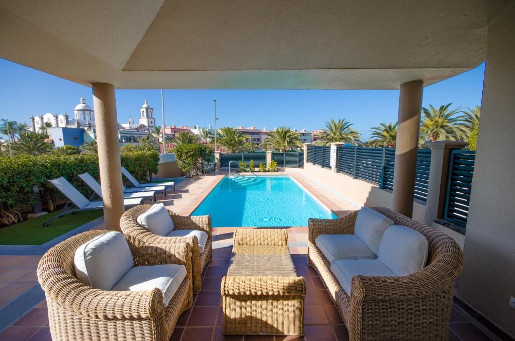 梅罗那瑞斯Villa Meloneras的一个带藤椅的庭院和一个游泳池
