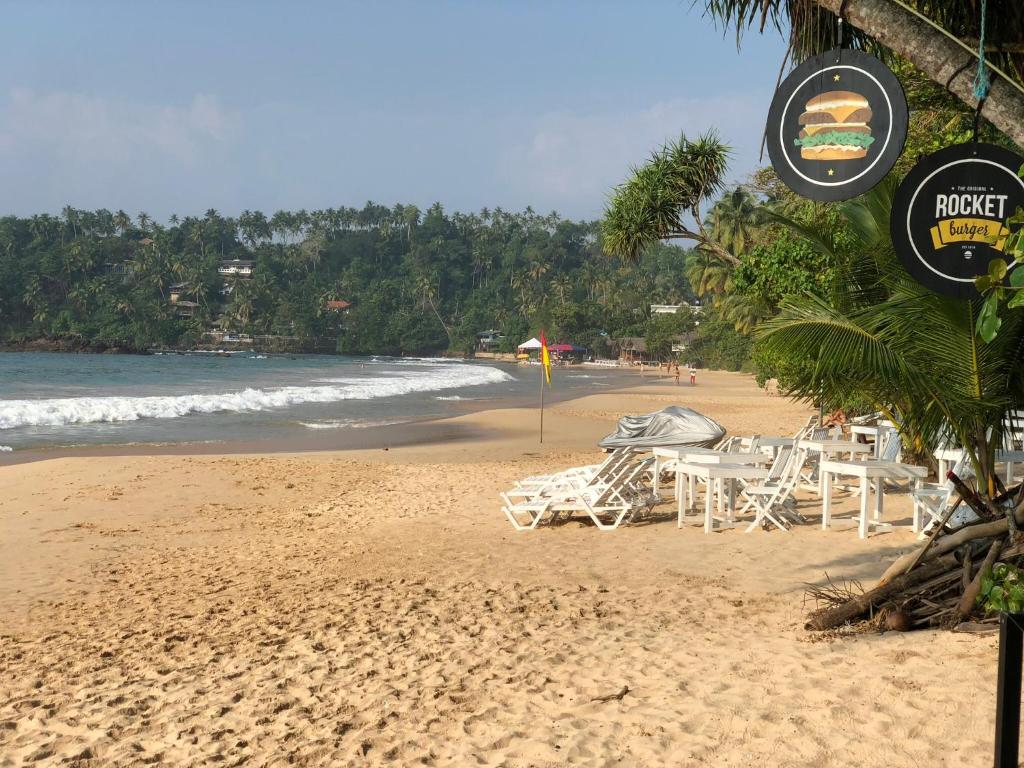 米瑞莎斯拉小屋酒店的海滩上设有桌椅,大海上设有沙滩