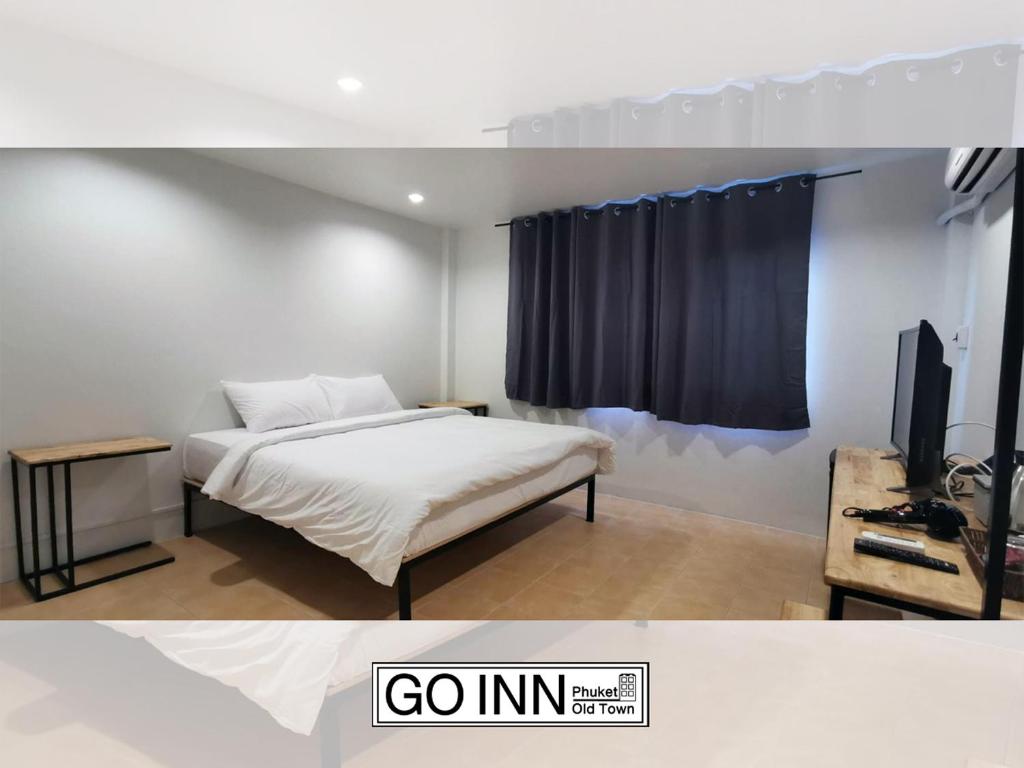 普吉镇Go Inn Phuket old Town的一间卧室配有一张床,并在一间客房内配有电视。