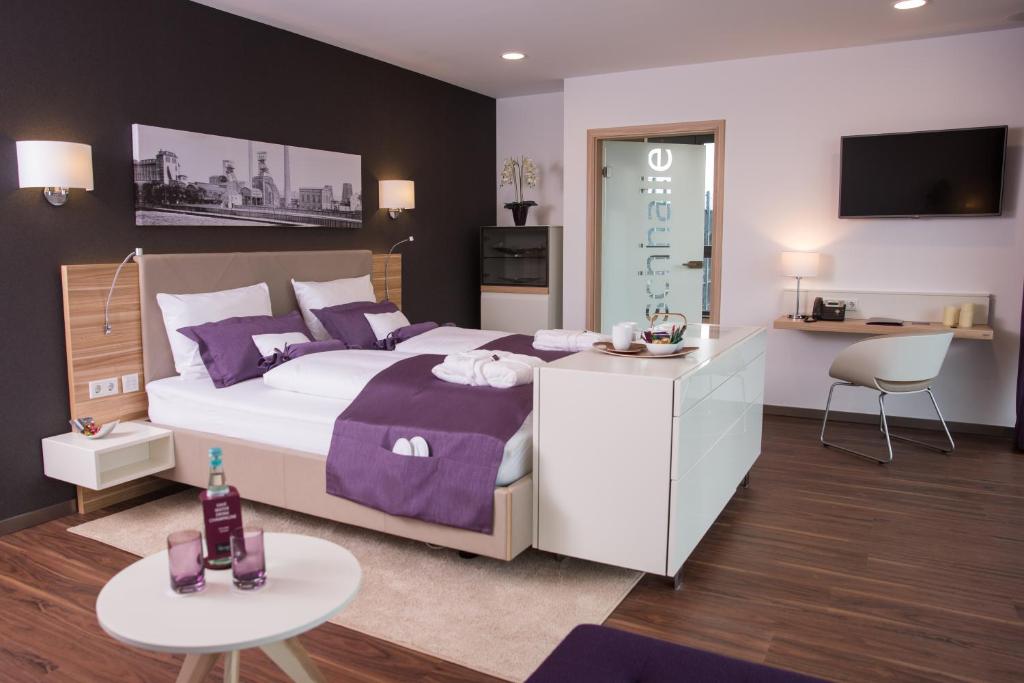 盖尔森基兴海纳公园酒店的一间卧室配有一张带紫色枕头的大床