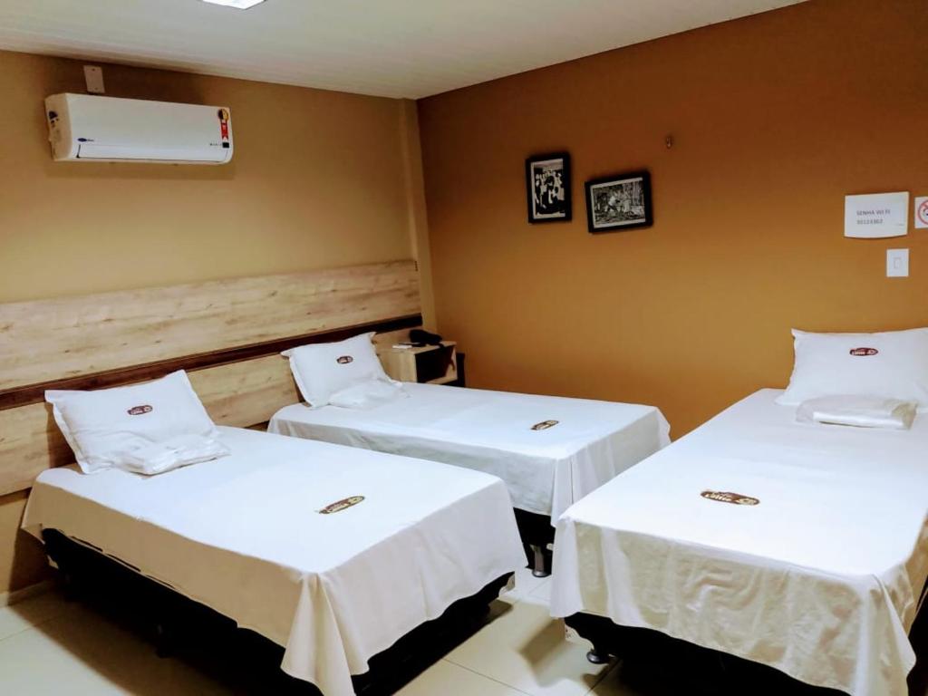 北茹阿泽鲁Pousada Café Com Leitte的配有白色床单的客房内的两张床