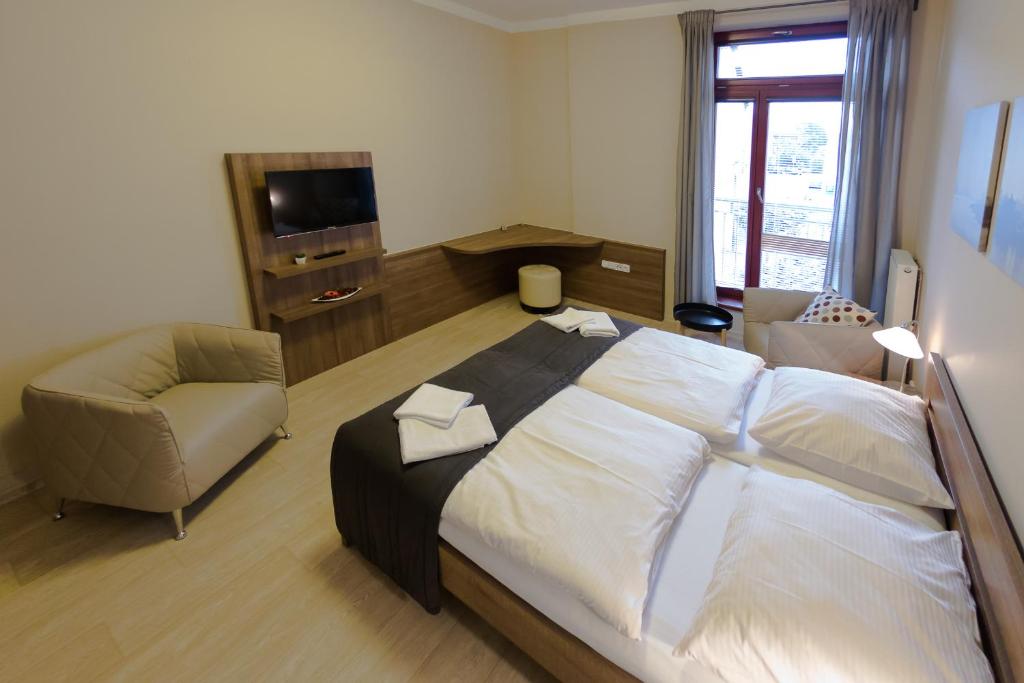 波杰布拉迪Penzion Apartmány Resident的一间卧室配有一张大床和一把椅子