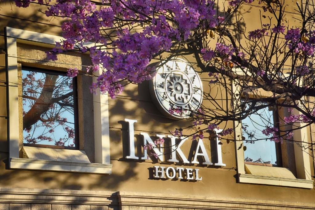 萨尔塔Hotel Inkai的紫色花朵的酒店一侧的钟