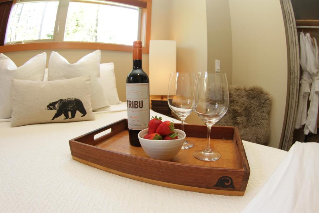 托菲诺黑熊旅馆 的床上的一瓶葡萄酒和一碗水果及酒杯
