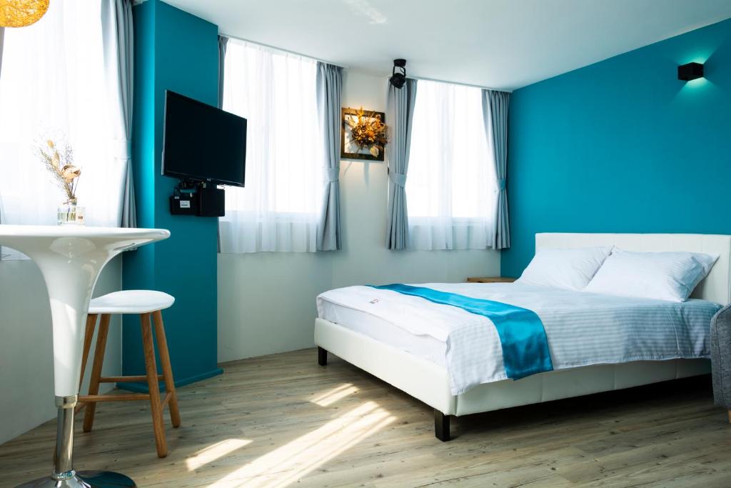 台南沐蓝轻旅的一间蓝色卧室,配有一张床和电视