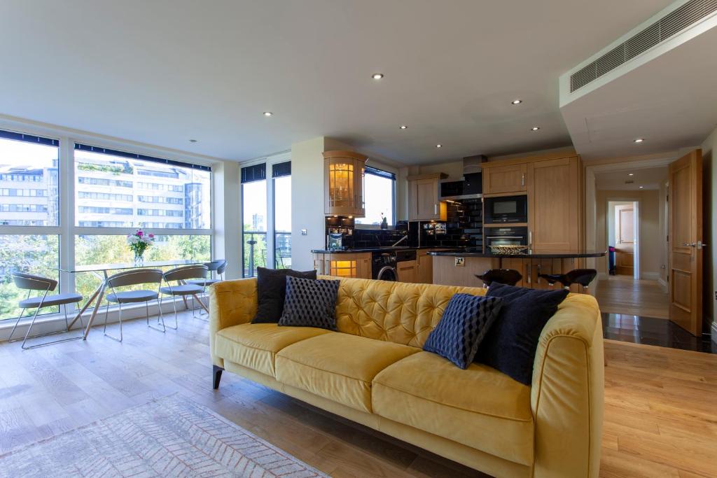 伦敦Thames View Apartment, Imperial Wharf的一间带黄色沙发的客厅和一间厨房
