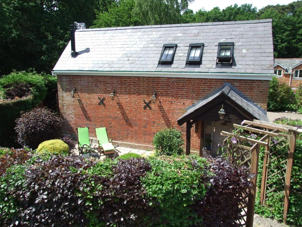 莱德林赫The Barn的花园内带两把绿色椅子的砖房