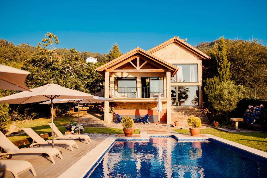 马林Bosque de Xarás, casa completa con encanto cerca de playa de Lapamán的房屋前有游泳池的房子