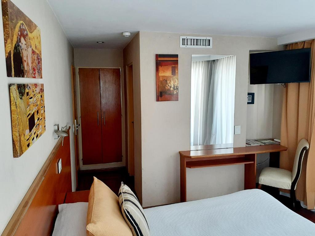 拉普拉塔贝内文托酒店的小房间,设有一张床和一扇红色的门