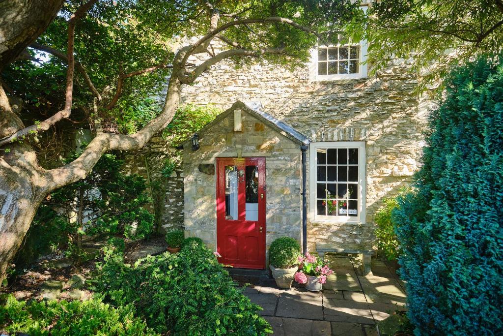里士满Nuns Cottage Bed & Breakfast的一座石头房子,有红门和一棵树