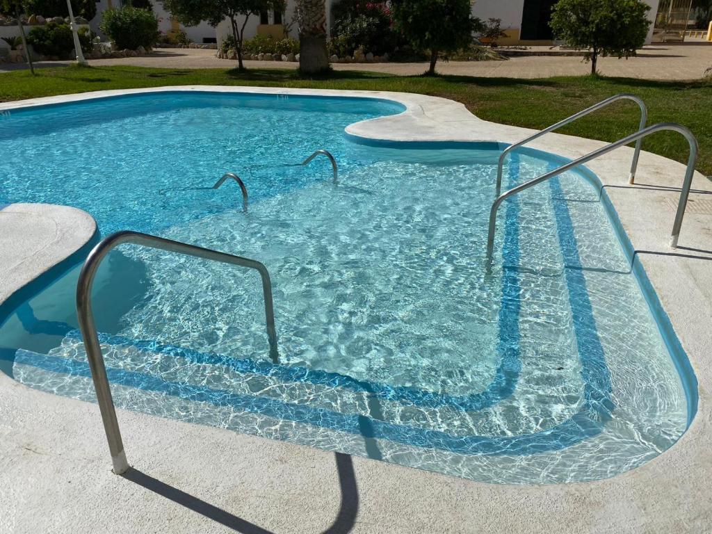 滨海罗克塔斯Apartamentos Roquetas Beach的一个带蓝色水和金属栏杆的游泳池
