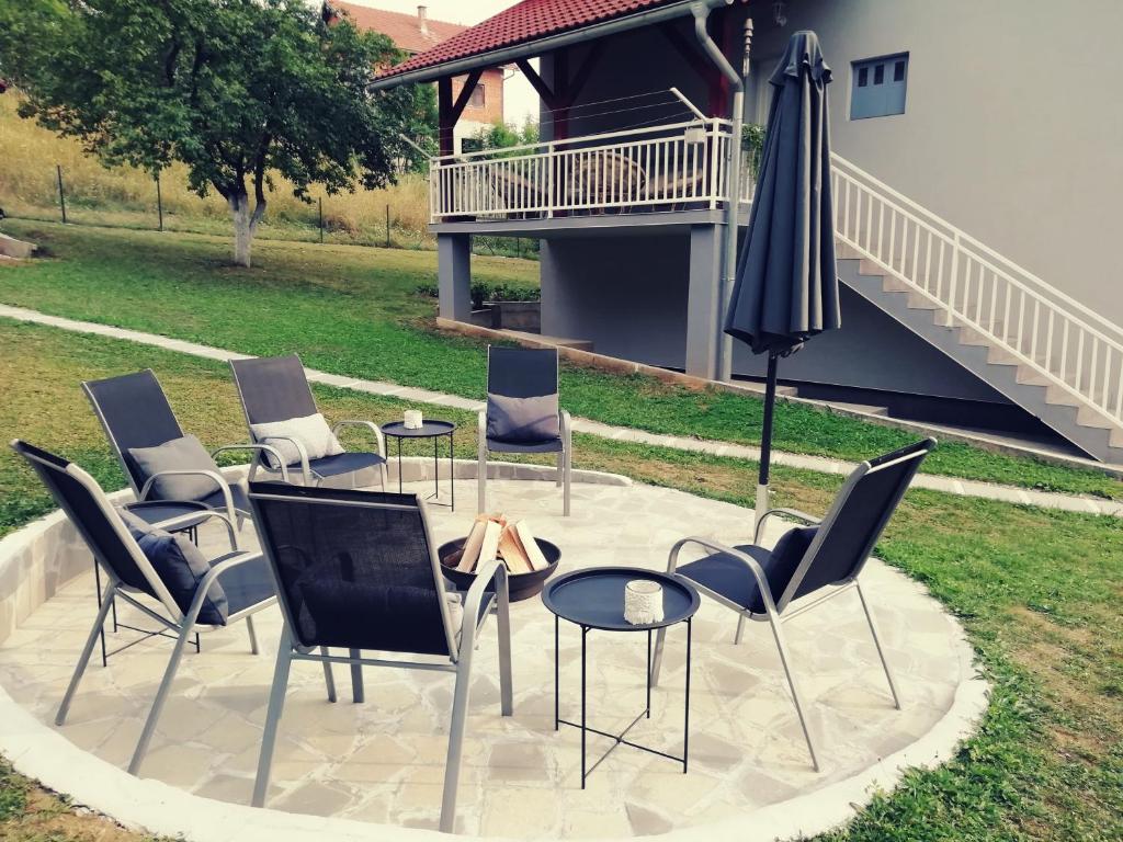 UdbinaArtisan House Meraki的庭院里摆放着一组椅子和一把遮阳伞