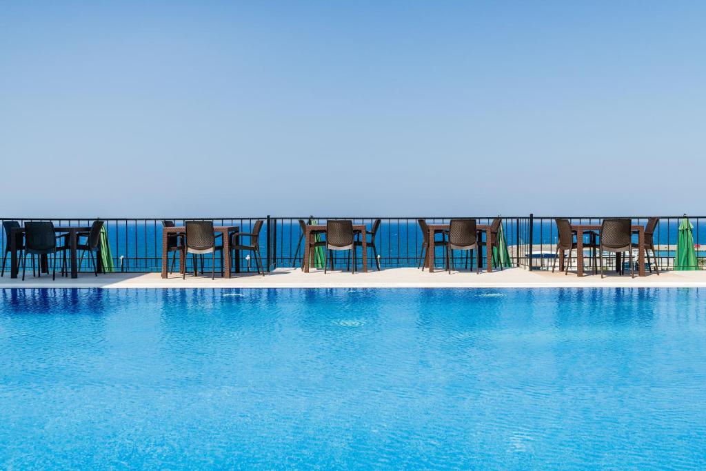 凯里尼亚Olivia Palm Hotel的一个带椅子的游泳池,海水蓝色