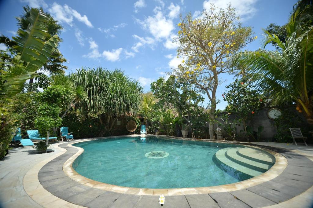 佩母德兰巴厘岛佩母得兰芙蓉住宿加早餐旅馆的一座大游泳池,位于一个树木繁茂的庭院内
