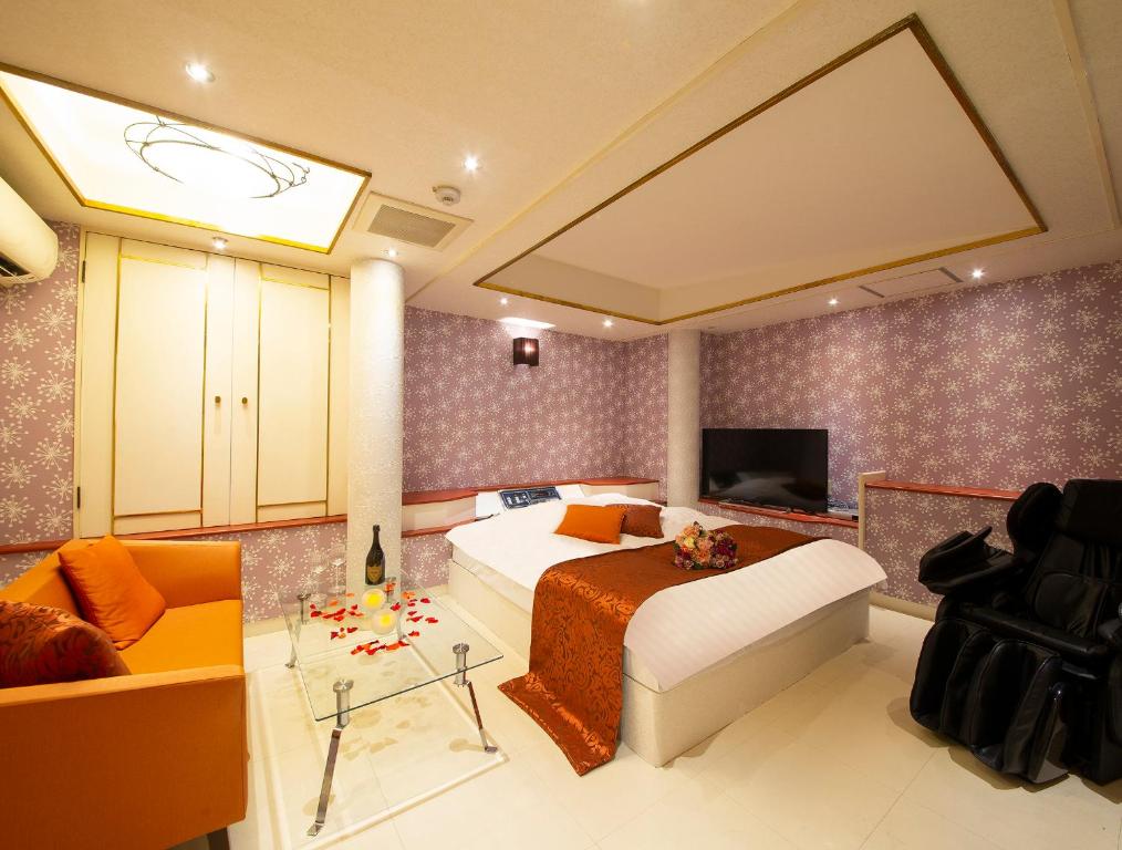 堺市Hotel Gee (Adult Only)的一间卧室配有一张床、一张沙发和一台电视。