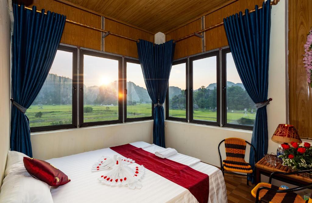 宁平Hang Mua Central Homestay的一间卧室配有一张带蓝色窗帘和窗户的床。