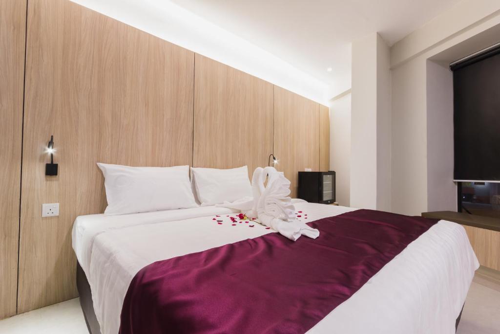 关丹GM Hotel Kuantan的一间卧室配有一张大床和紫色毯子