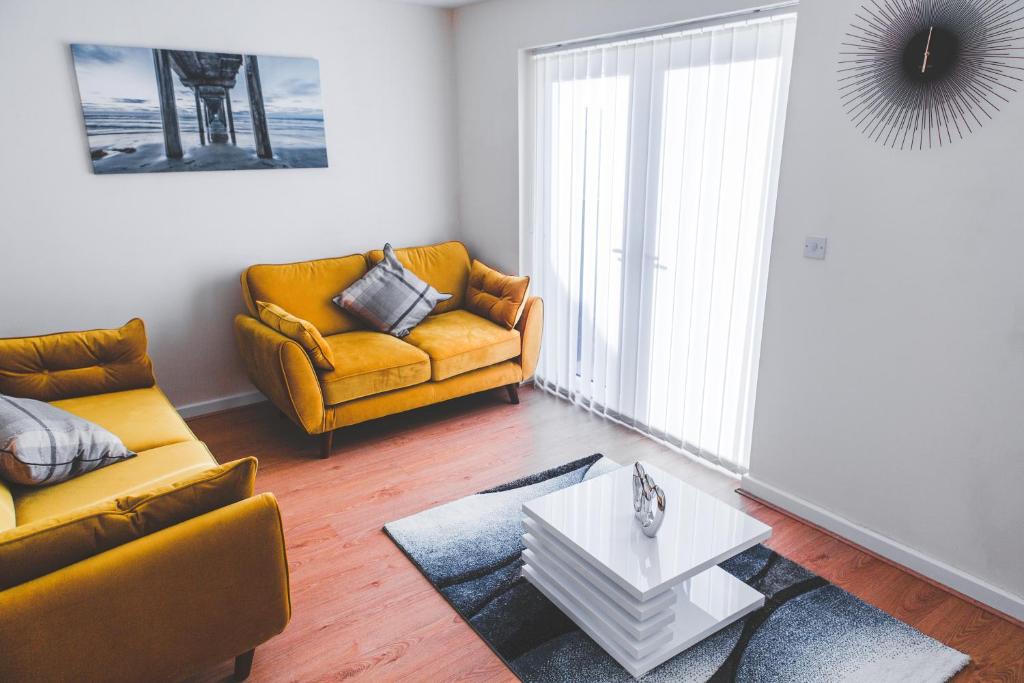 曼彻斯特Salford Holiday Apartment Manchester的客厅配有两张黄色的沙发和一张桌子