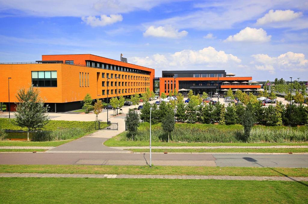 阿尔梅勒阿尔梅勒范德瓦尔克酒店的一座橙色的建筑,前面设有停车场