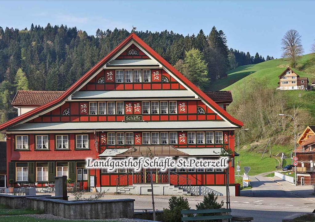 Sankt PeterzellLandgasthof Schäfle的一座红色的大建筑,上面有标志