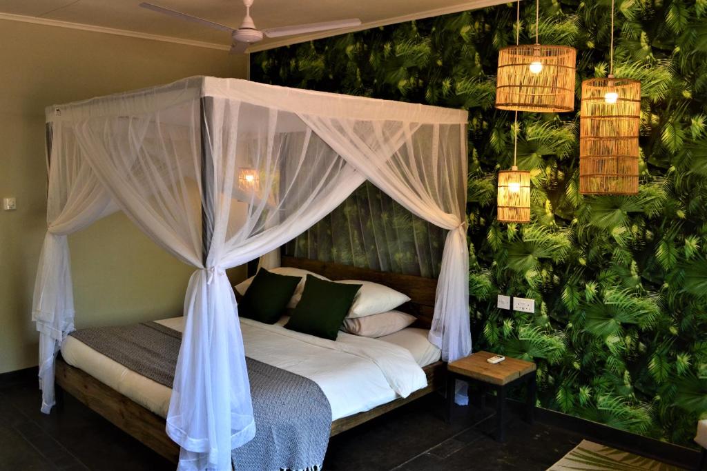 利隆圭Mitengo House的一间卧室配有绿树成荫的天蓬床