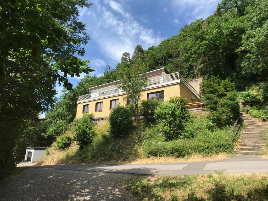 施莱登Villa Holgenbach - Penthouse- und Ferienwohnung im Nationalpark Eifel的山边的黄色房子