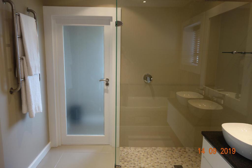 普利登堡湾Twin Rivers Villa的一间带两个水槽和玻璃淋浴间的浴室