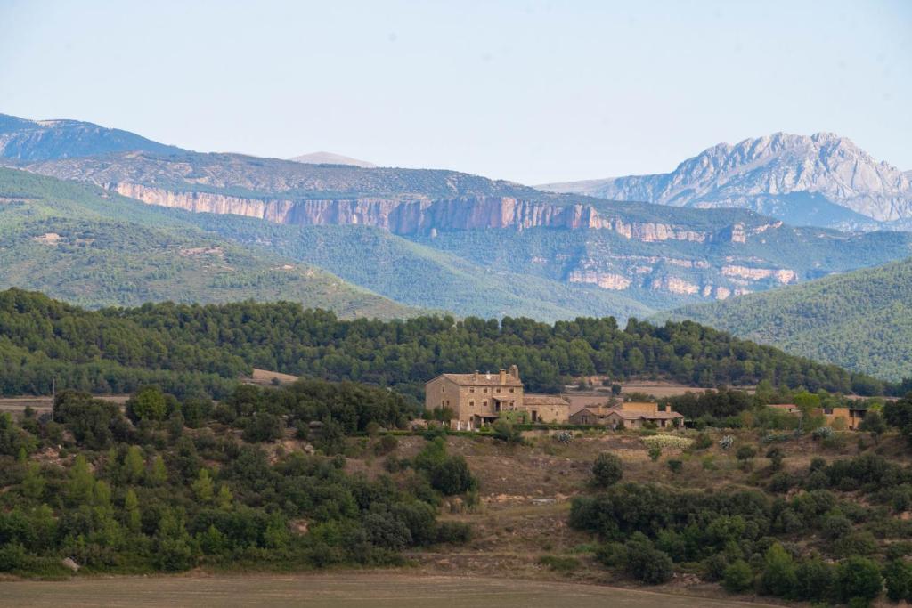 索尔索纳Casa rural Sant Grau turismo saludable y responsable的山丘上以山为背景的房子