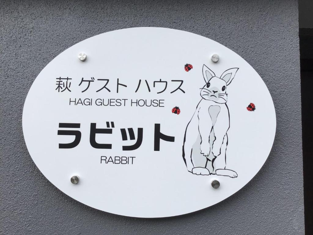 萩市萩ゲストハウスラビット的墙上挂着猫的照片的标志