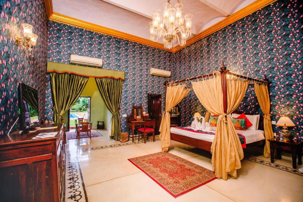 阿格拉格兰德皇家遗址酒店的一间卧室,卧室内配有一张天蓬床