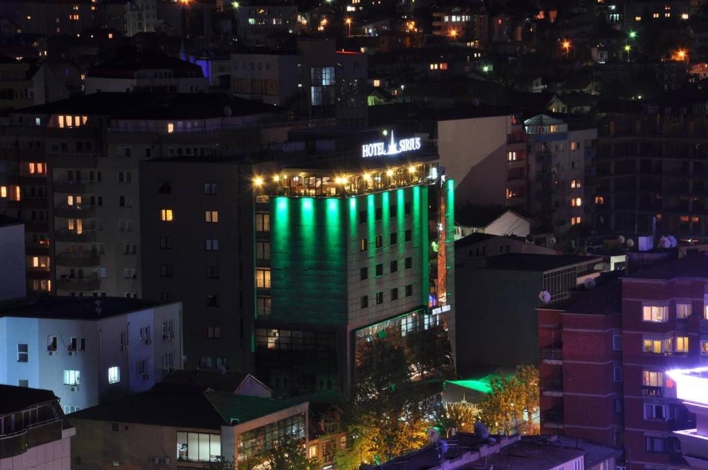 普里什蒂纳天狼星酒店 的一座高大的建筑,晚上有绿灯
