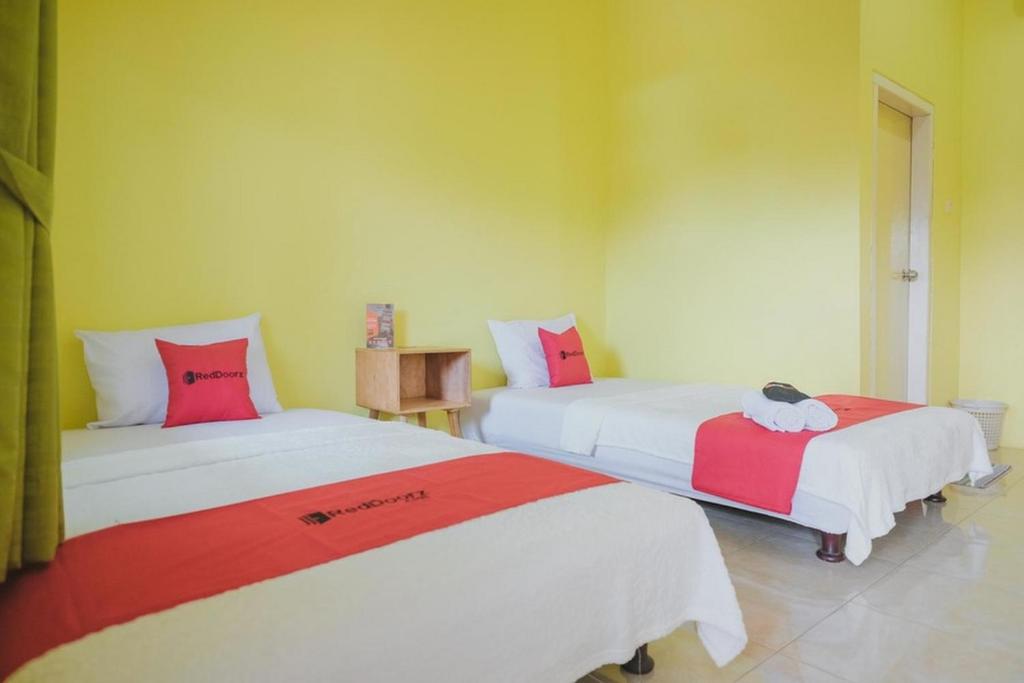 占碑市RedDoorz Syariah near Kantor Walikota Jambi的一间设有两张红色和白色床单的房间