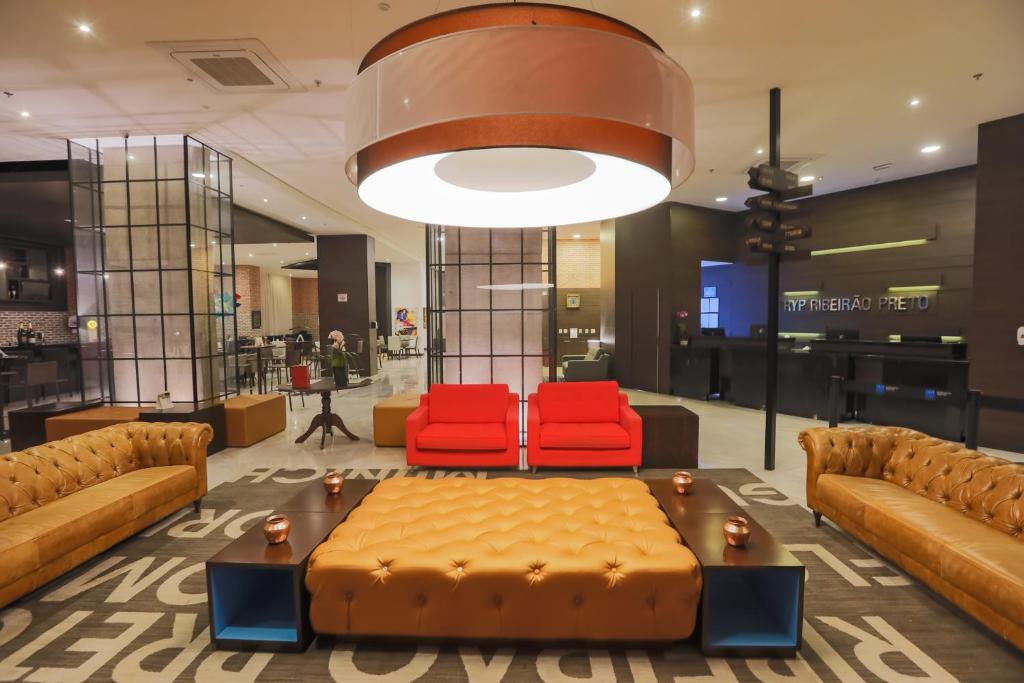 里贝朗普雷托TRYP By Wyndham Ribeirão Preto的大堂配有沙发和2把红色椅子