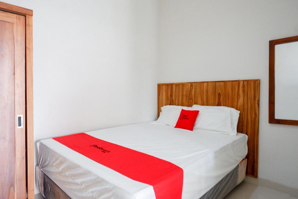 直葛RedDoorz Plus Syariah near Stasiun Tegal 2的卧室配有白色的床和红色毯子
