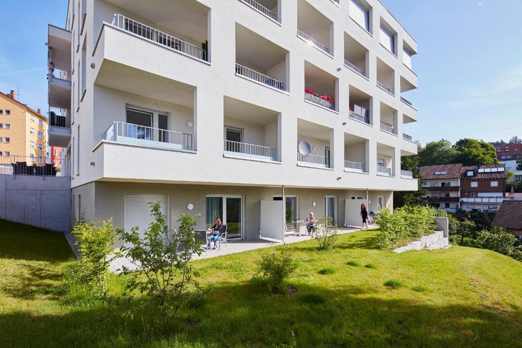 黑林山区圣格奥尔根AusZeit的一座白色的公寓楼,里面的人坐在院子里